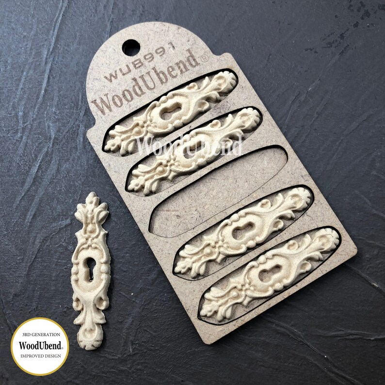 May include: A set of four unfinished wooden keyhole covers with ornate designs. The covers are packaged on a card with the text "WoodUbend" and "WUB991".