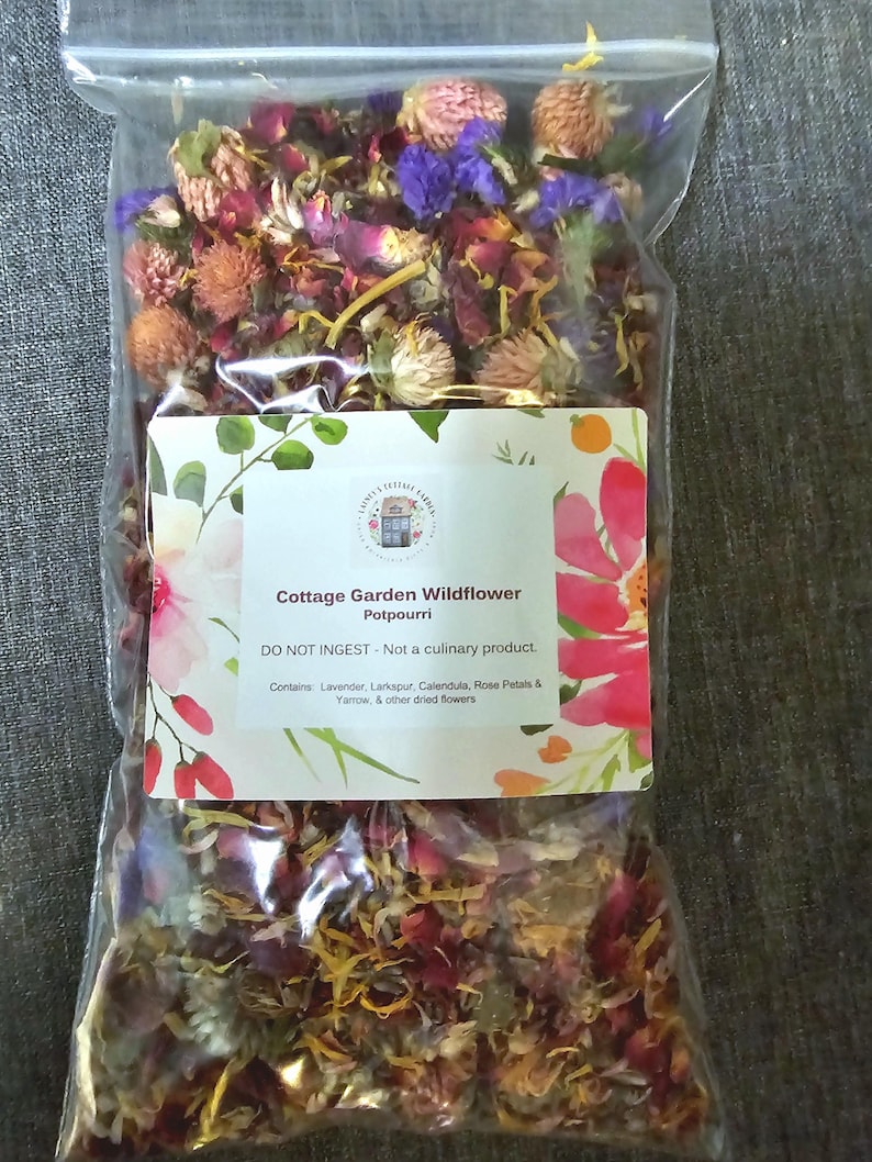 May include: A clear plastic bag filled with dried flowers, including pink, purple, and yellow petals. A white label features the text: Cottage Garden Wildflower Potpourri, DO NOT INGEST - Not a culinary product. Contains: Lavender, Larkspur, Calendula, Rose Petals & Yarrow, & other dried flowers.