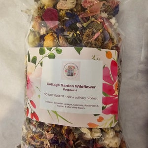 May include: A clear plastic bag filled with dried flowers including lavender, larkspur, calendula, rose petals, and yarrow. The label reads: Cottage Garden Wildflower Potpourri, DO NOT INGEST - Not a culinary product. Contains: Lavender, Larkspur, Calendula, Rose Petals & Yarrow, & other dried flowers.
