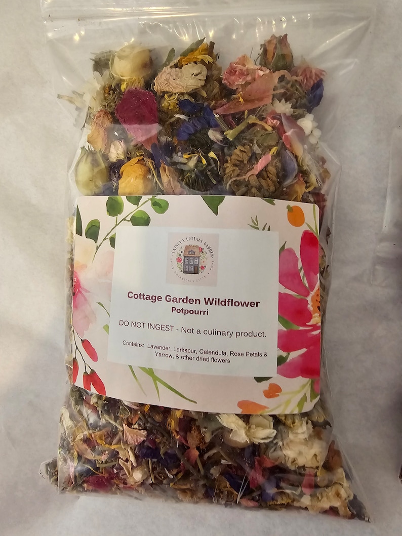 May include: A clear plastic bag filled with dried flowers including lavender, larkspur, calendula, rose petals, and yarrow. The label reads: Cottage Garden Wildflower Potpourri, DO NOT INGEST - Not a culinary product. Contains: Lavender, Larkspur, Calendula, Rose Petals & Yarrow, & other dried flowers.