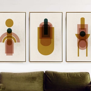 May include: Three abstract geometric art prints with a cream background. The prints feature overlapping circles, squares, and rectangles in shades of yellow, brown, and pink.