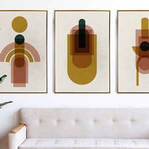 May include: Three abstract geometric art prints with a beige background. The prints feature overlapping shapes in shades of brown, yellow, and teal.