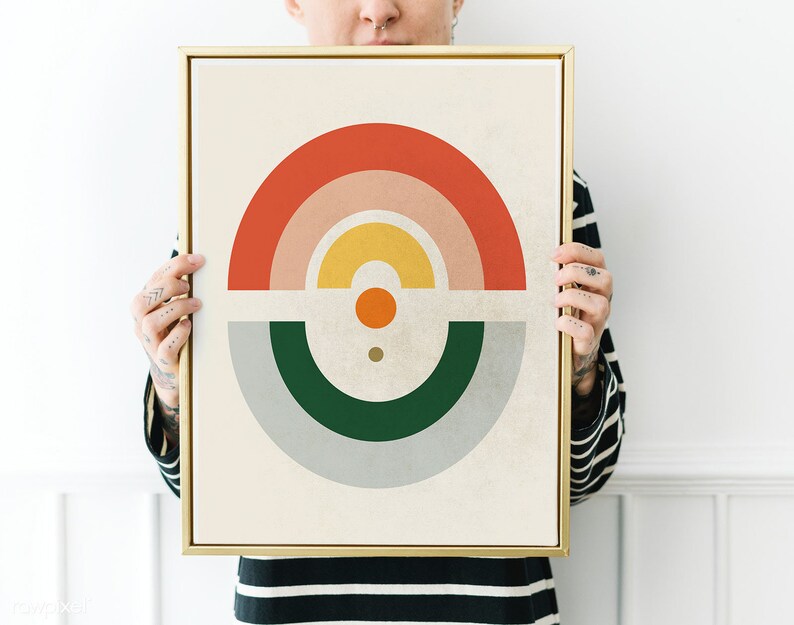 May include: A framed abstract art print featuring a geometric design with a rainbow of colors. The artwork includes a red, pink, yellow, and orange arch, with a green and gray semi-circle below. The frame is gold.