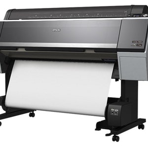 Pu&ograve; includere: Una stampante Epson di grande formato con un rotolo di carta bianca che la attraversa. La stampante &egrave; nera e argentata con un pannello di controllo in alto a destra. La stampante &egrave; su ruote e ha un supporto.