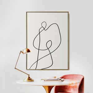 May include: A black and white abstract line art print in a gold frame. The print features a single continuous line that forms a shape resembling a person.