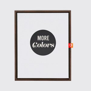 May include: A framed print with a black circle and white text that reads "MORE COLORS" on a white background.