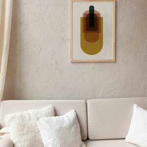 May include: A framed abstract print with a geometric design featuring overlapping shapes in shades of brown, yellow, and blue. The print is on a white background and has a wooden frame.