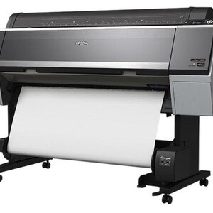May include: A large format Epson SureColor printer with a roll of white paper feeding through it. The printer is black and silver with a black base and wheels.