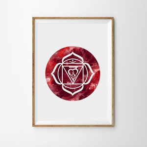 May include: Framed print featuring a white chakra symbol over a red watercolor background. The symbol is a geometric design with a central figure, set within a circular shape. The frame is a light brown color.