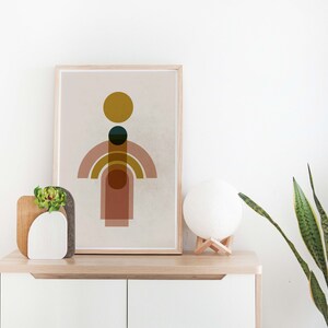 May include: A framed print with a minimalist geometric design featuring a yellow circle, a dark green circle, and overlapping pink and brown arches on a beige background.