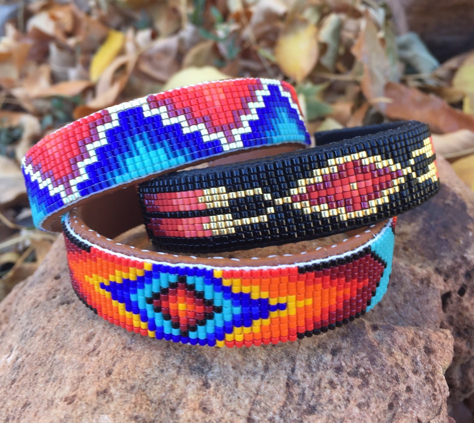 Beaded Two Feather Bracelet in Reds and Gold on a Black Background