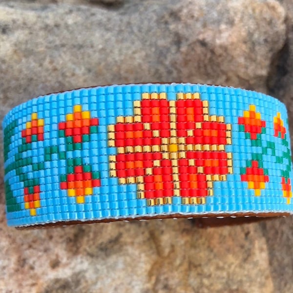 Light Reds and Gold Floral Beaded Bracelet on a Sky Blue Background. This Beautiful Floral Piece would complement many a outfit.