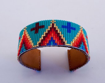 Beaded bracelet in Gold, Reds and Blues on a Turquoise Background. A Striking piece for Men and Women.