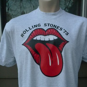 May include: A gray t-shirt with a red tongue and lips graphic and the text "Rolling Stones '75".