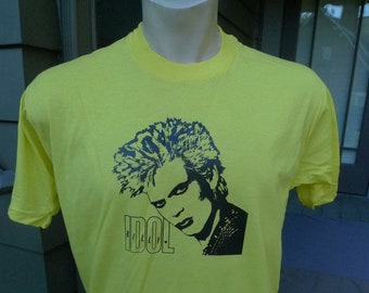 May include: A neon yellow t-shirt with a black and white image of Billy Idol. The text "Billy Idol" is printed below the image.