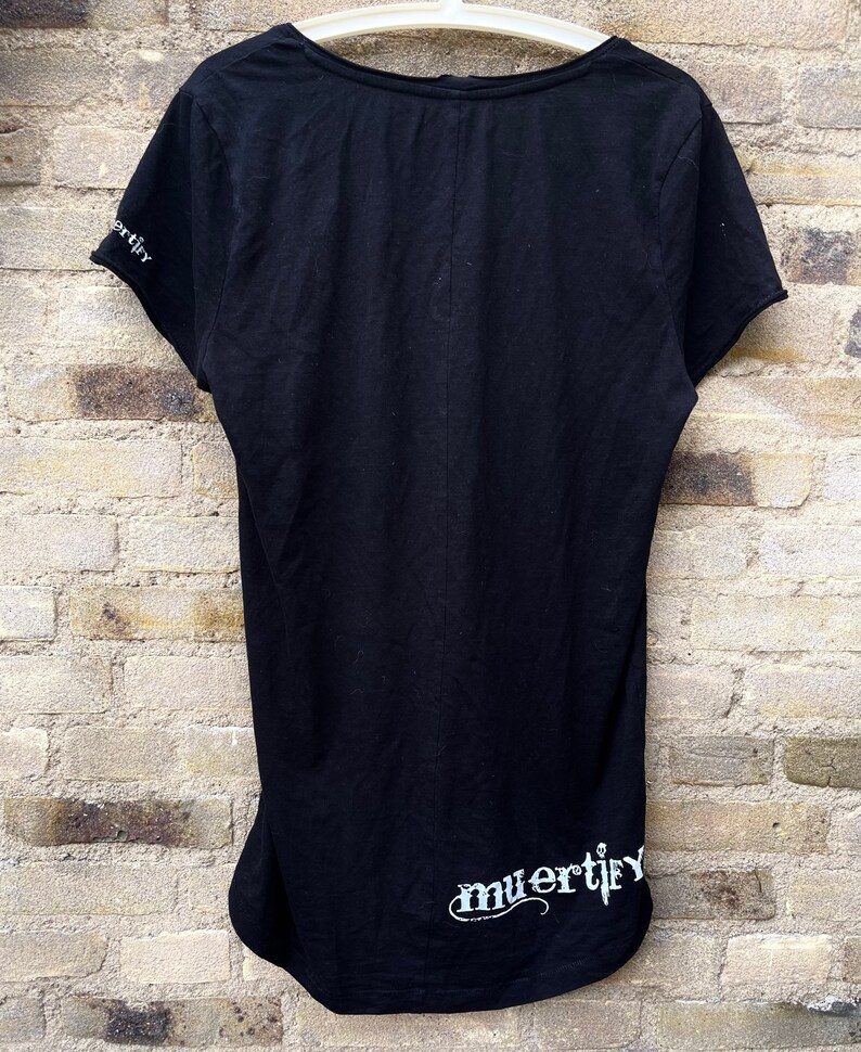Puede incluir: Camiseta negra con un gr&aacute;fico blanco que dice "muertify" en el dobladillo inferior.