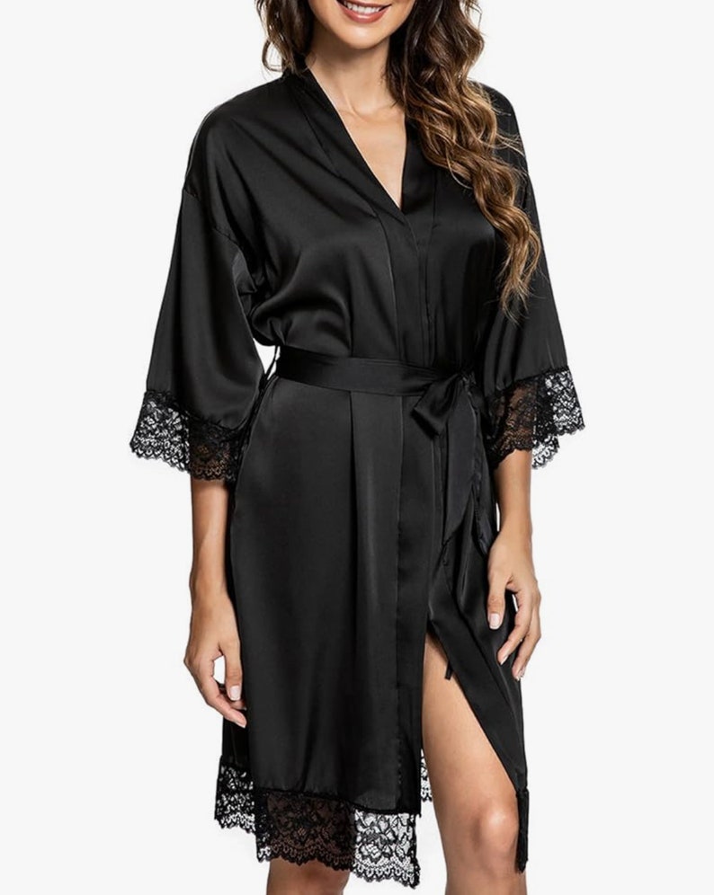 May include: A black satin robe with lace trim around the sleeves and hem. The robe has a tie belt and a front opening.