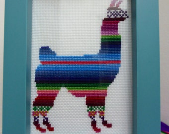 May include: A framed cross-stitch of a llama with a colorful striped pattern. The llama is standing on a white background and is framed in a teal frame.