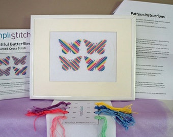 May include: A counted cross stitch kit featuring four colorful butterflies with rainbow stripes. The kit includes embroidery floss, a needle, and instructions. The kit is called "Beautiful Butterflies" by "SimplistStitch".