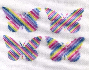 May include: Four colorful butterfly cross-stitch patterns on a white background. Each butterfly is made of pink, purple, yellow, and blue thread.