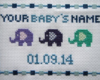 May include: A white cross-stitch embroidery with a blue border. The embroidery features the text "YOUR BABY'S NAME" and the date "01.09.14". Three embroidered elephants are featured in purple, blue, and green.