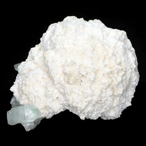 May include: A large, textured, white mineral formation with a rough, crystalline surface. Several translucent, light blue-green crystal formations are attached to the base of the white mineral. The background is solid black.