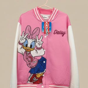 May include: Pink and white varsity jacket featuring a large Daisy Duck graphic with glitter accents. The jacket has white sleeves, a striped collar and cuffs, and the name "Daisy" in glitter lettering. A "Pat Pat" tag is attached.