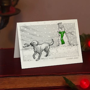 Dog and Snowman - Petite carte de Noel (A7) Impression magnifiquement dessinée sur le stock de cartes de qualité blanc cassé. GRATUIT pour les commandes de cartes au Royaume-Uni.