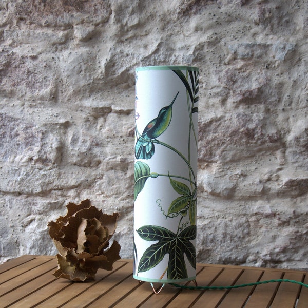 Lampe à poser abat-jour conique habillé de papier peint tropical colibri sur polyphane blanc.