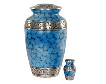 May include: A set of two blue and silver cremation urns. The larger urn has a marbled blue finish with silver floral accents. The smaller urn is a solid blue with silver accents.