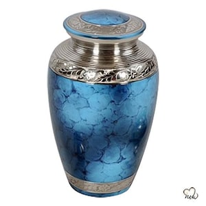 May include: A blue and silver cremation urn with an ornate design. The urn has a silver lid with a floral pattern and a blue body with a marbled effect.