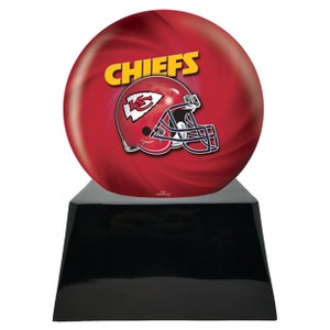 May include: A red and yellow Chiefs football helmet and team name are displayed on a red bowling ball. The bowling ball sits atop a black, glossy, trapezoid-shaped base. The image is a sports-themed decorative item.
