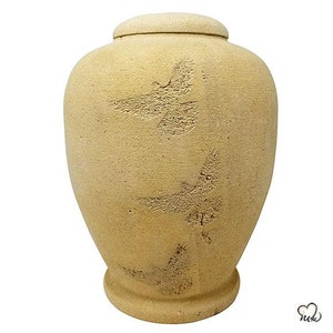 May include: A beige ceramic urn with a textured surface and a design of stylised birds. The urn has a lid.