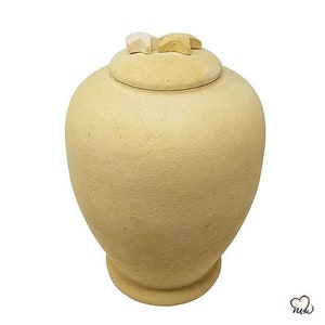 May include: A beige ceramic urn with a lid decorated with three small stars. The stars are made of a light brown material.