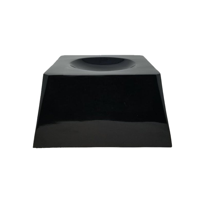 May include: A glossy black display stand with a square top and a circular indentation. The stand has a trapezoidal base and is designed to showcase an object. The stand is made of a solid material and has a reflective surface.