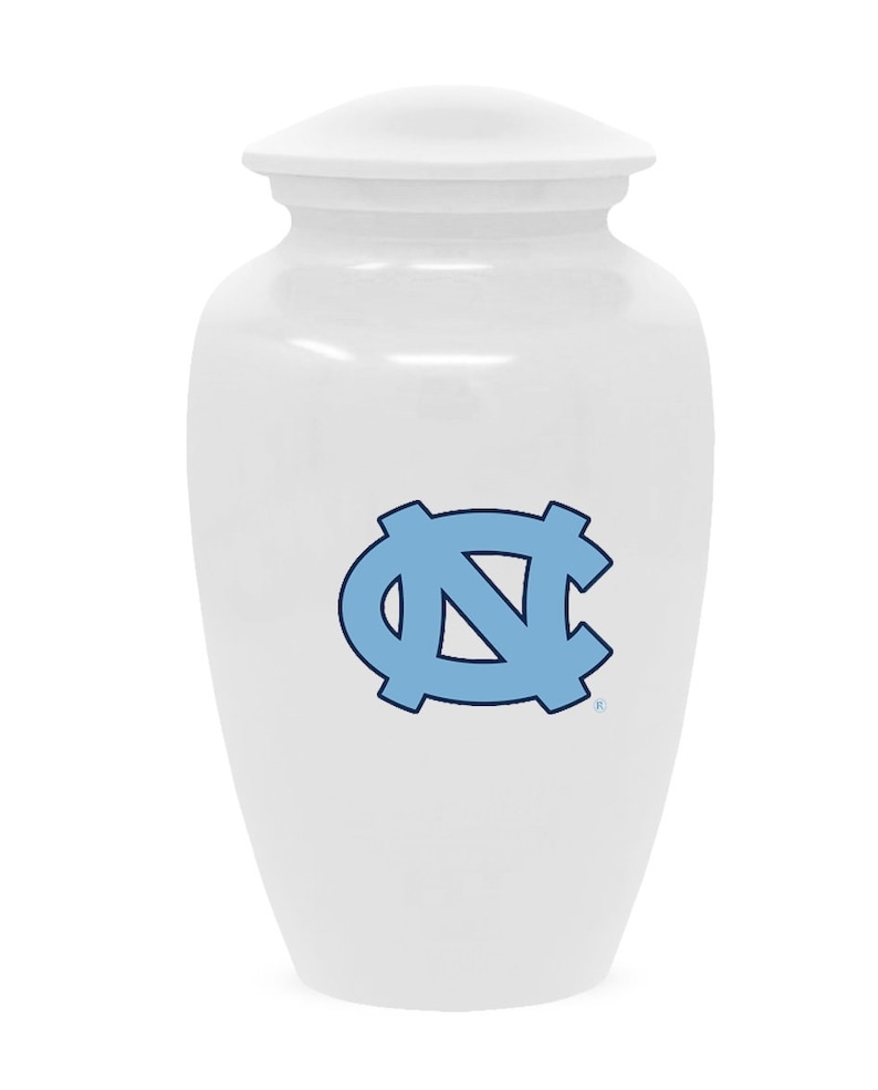Puede incluir: Urna de cer&aacute;mica blanca con un logotipo azul y blanco de la Universidad de Carolina del Norte Tar Heels.