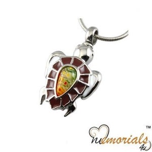 Puede incluir: Colgante de tortuga de plata con una incrustación de vidrio multicolor. La tortuga es un símbolo popular de longevidad y buena suerte.