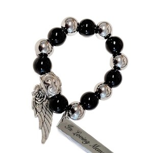 May include: A beaded bracelet featuring alternating black and silver-colored beads. A silver charm with an angel wing and rose design is attached, along with a rectangular tag that reads "In Loving Memory".