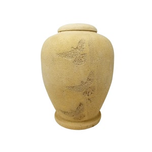 May include: A beige ceramic urn with a textured surface and three stylised bird designs.