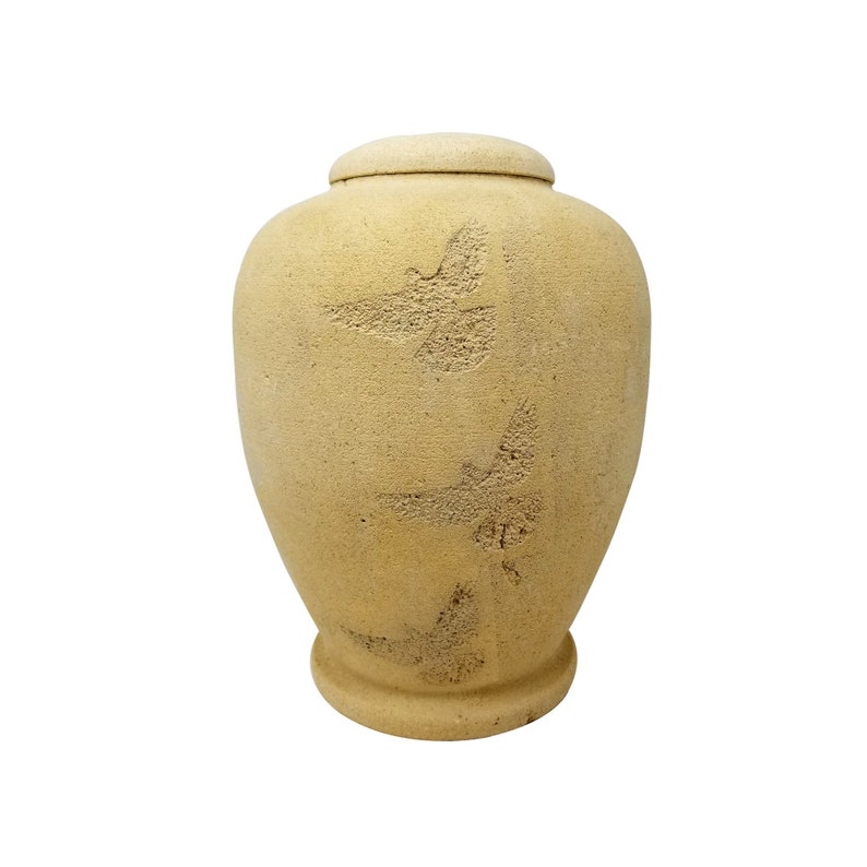 May include: A beige ceramic urn with a textured surface and three stylised bird designs.