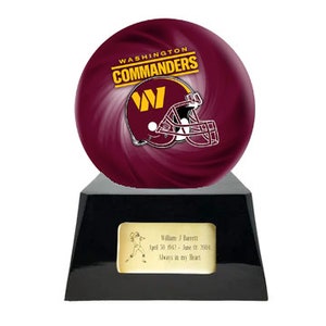 May include: A burgundy bowling ball featuring the Washington Commanders logo, displayed on a black base with a gold plaque. The plaque includes a name, dates, and a football player illustration.