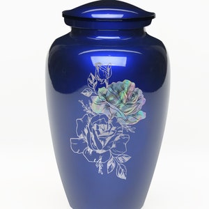 May include: A blue metal urn with a floral design featuring two roses and leaves. The roses are engraved with a pearlescent finish.