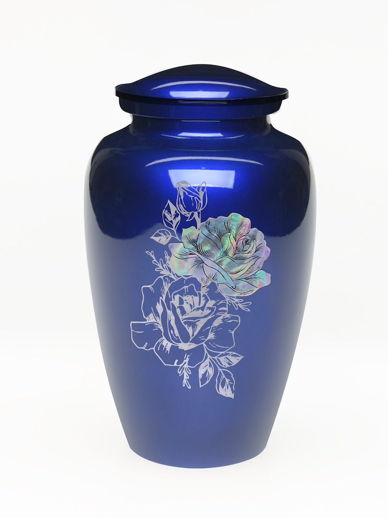 May include: A blue metal urn with a floral design featuring two roses and leaves. The roses are engraved with a pearlescent finish.