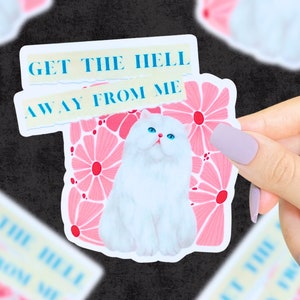 May include: A white sticker featuring a white cat with blue eyes sitting on a pink floral background. The sticker has the text "GET THE HELL AWAY FROM ME" in blue and white.