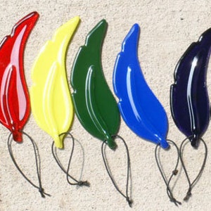 Puede incluir: Ocho adornos de vidrio en forma de hoja en varios colores, incluyendo rojo, amarillo, verde, azul y morado. Cada hoja tiene una cuerda para colgar.