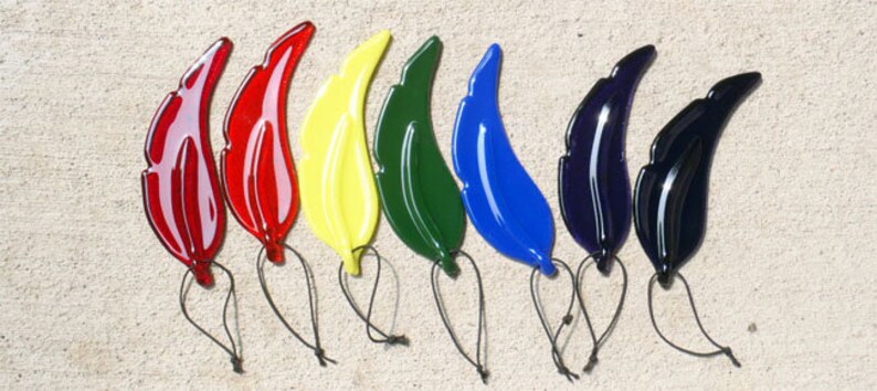 Puede incluir: Ocho adornos de vidrio en forma de hoja en varios colores, incluyendo rojo, amarillo, verde, azul y morado. Cada hoja tiene una cuerda para colgar.