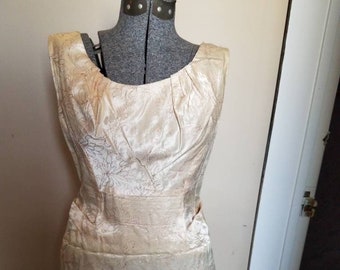 May include: A sleeveless, ivory satin dress with a floral pattern. The dress has a fitted bodice and a slightly flared skirt.