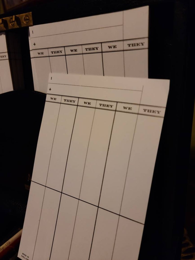 Op de afbeelding: Een wit gekarteld papier met de woorden "WE" en "THEY" die bovenaan worden herhaald. Het papier is in 12 secties verdeeld door zwarte lijnen.