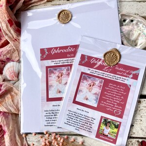 May include: Two signed art prints of a watercolor painting of Aphrodite, the Greek goddess of love and beauty. The prints are framed in clear plastic sleeves with a wax seal. The smaller print is 6x7 inches and the larger print is 8x10 inches. The artist's name and a brief bio are included on the back of each print.