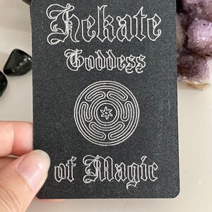 K&ouml;nnte beinhalten: Schwarze Karte mit wei&szlig;em Text und einem wei&szlig;en Symbol. Der Text lautet "Hekate G&ouml;ttin der Magie".